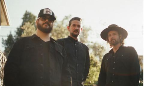 Bandmates from The Record Company wear black and pose outdoors.
